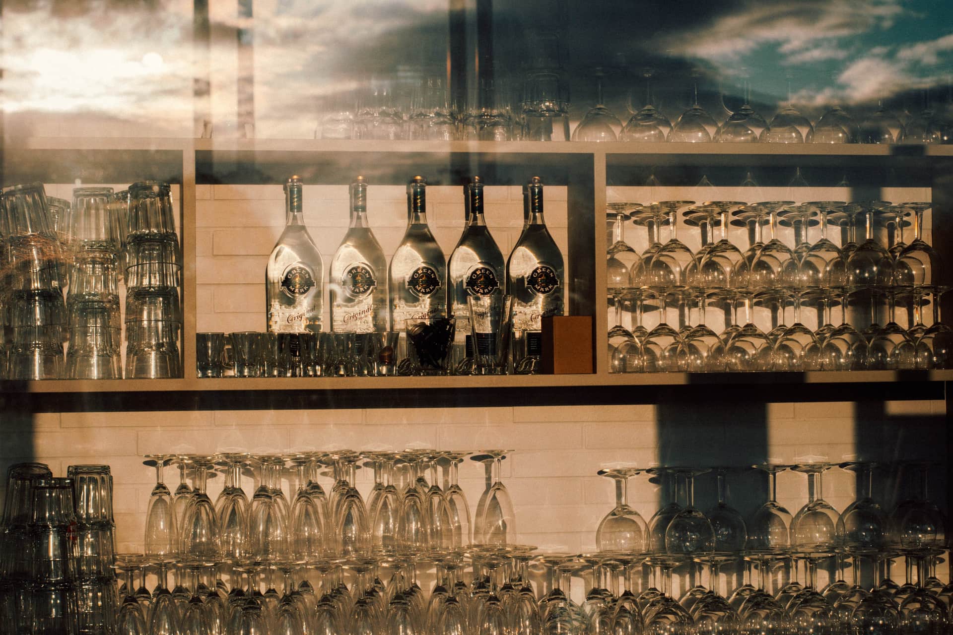 A bar shelf holding glassware and spirit bottles in warm light