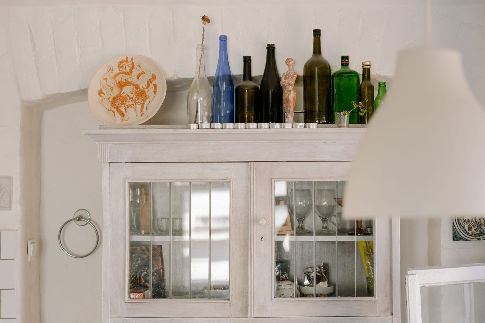 Green glass bottles standing on a painted wooden cupboard in a period interior
