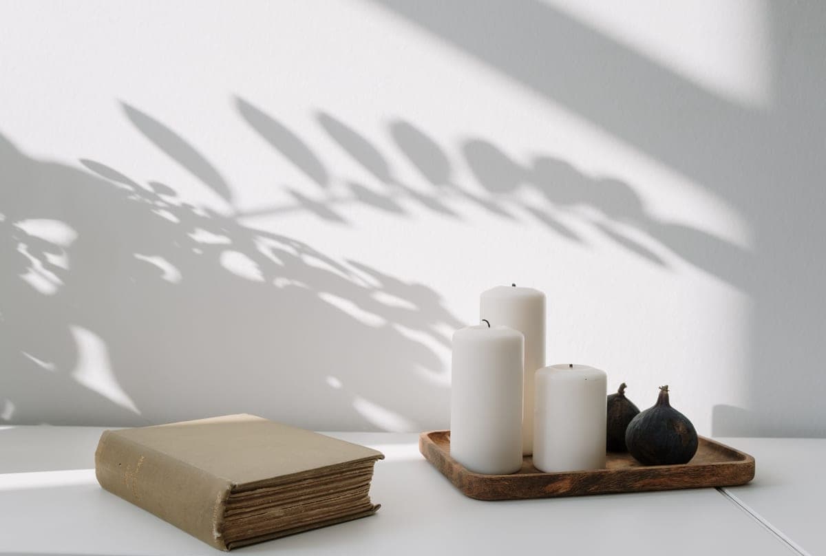 A decorative tray with candles and books arranged on a surface
