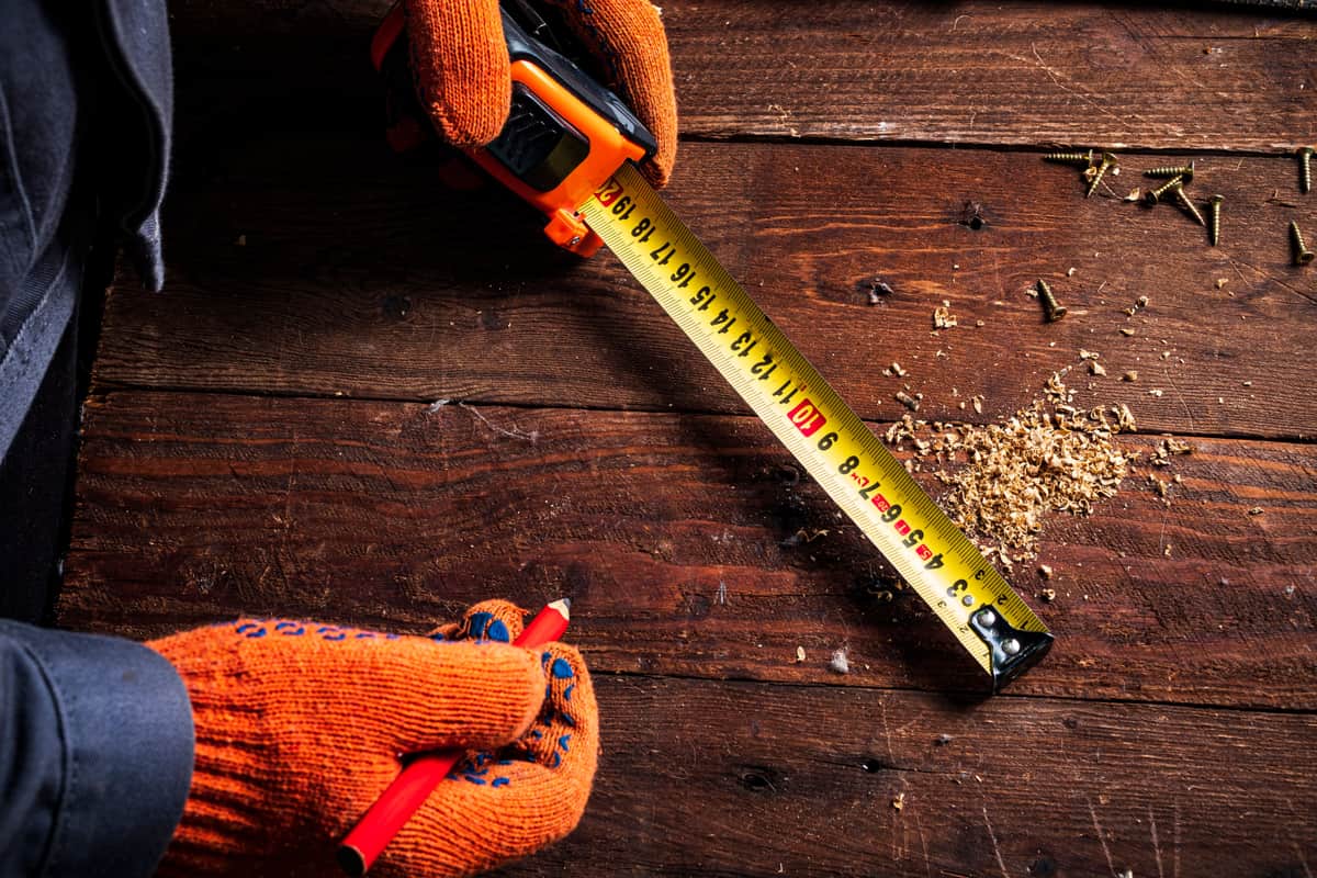 A tape measure extended across a piece of furniture on a wooden floor