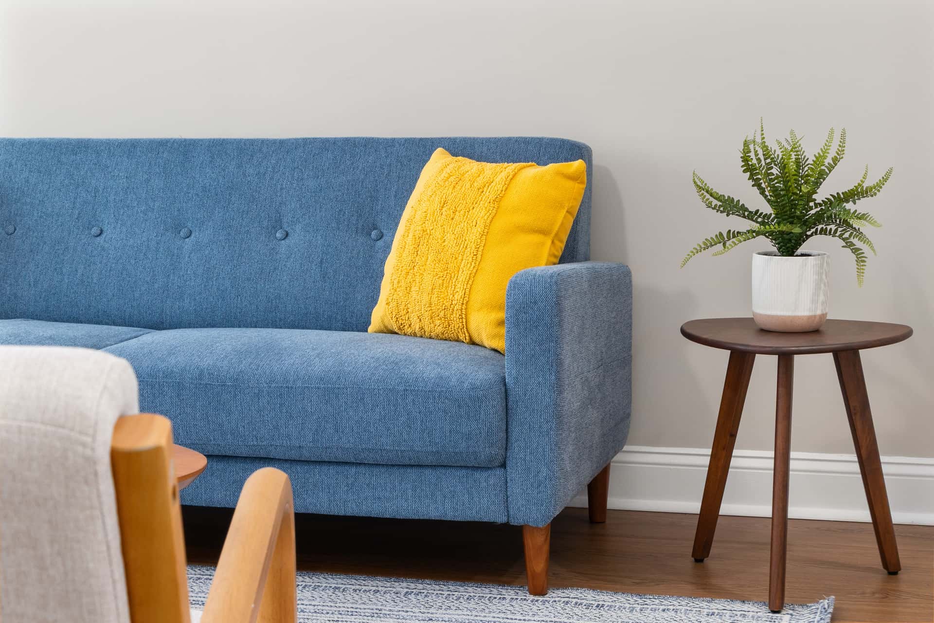 A contemporary living room with a blue sofa and a wooden side table