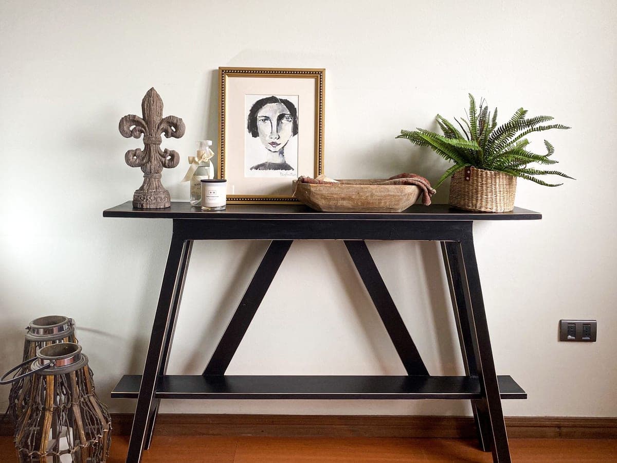 A console table styled with objects standing against a hallway wall