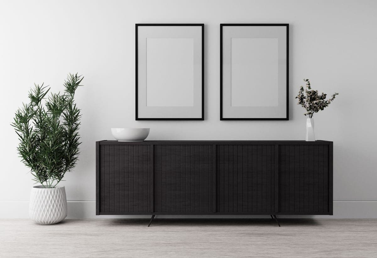 A long low sideboard against a wall in a living room with objects on top