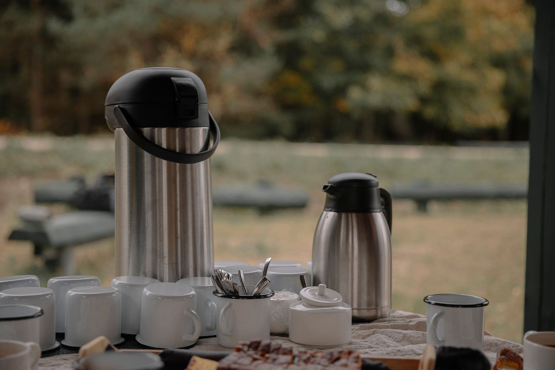A thermos, cups and snacks laid out on a table for a group