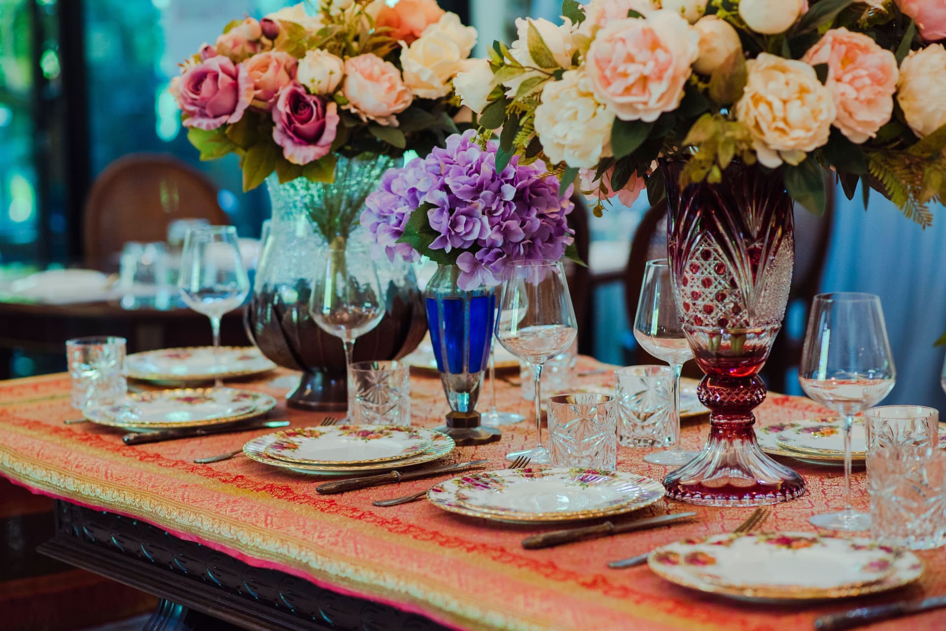 A dining table laid with vintage tableware and a floral arrangement