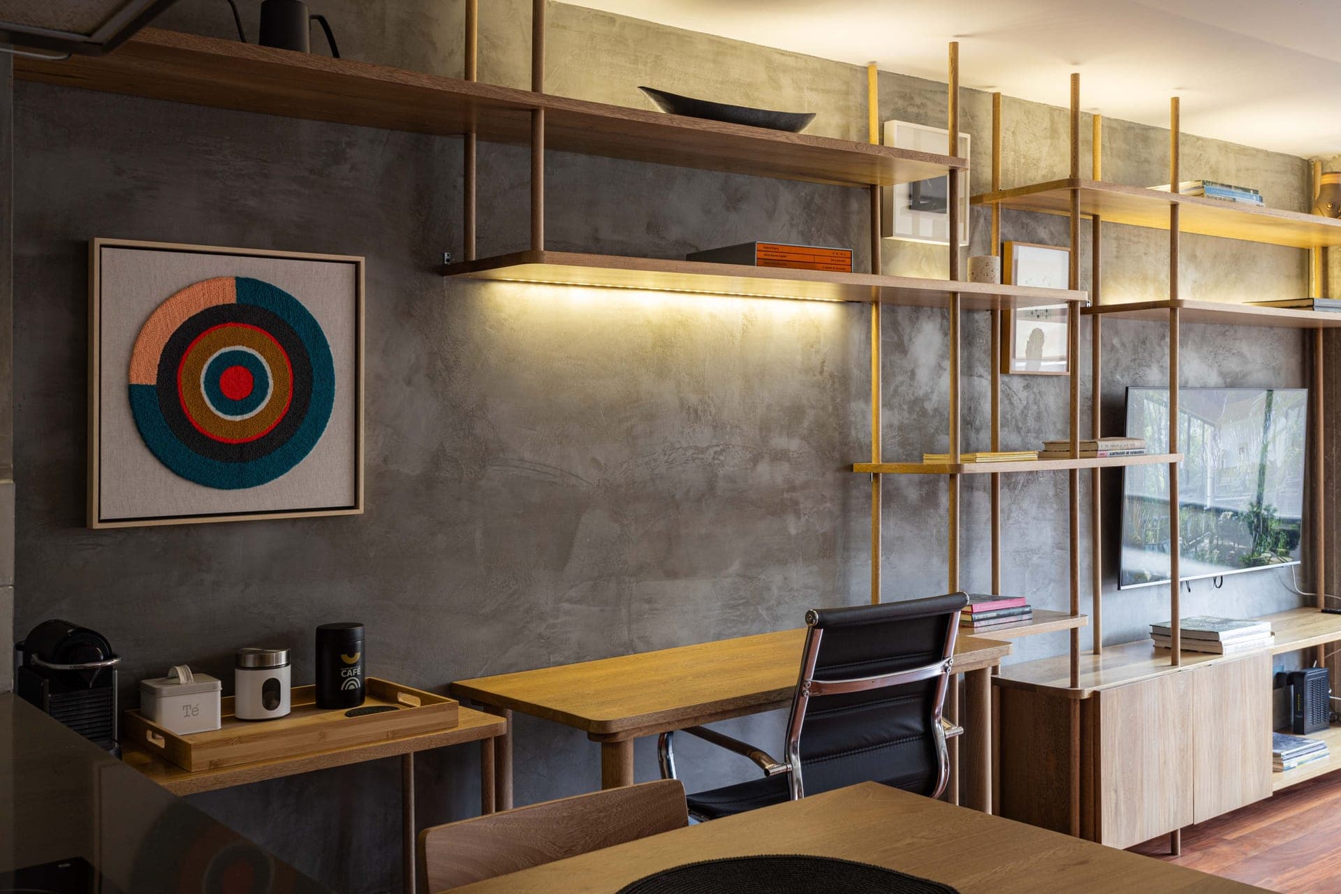 A home office with a wooden desk, open shelving and modern decor