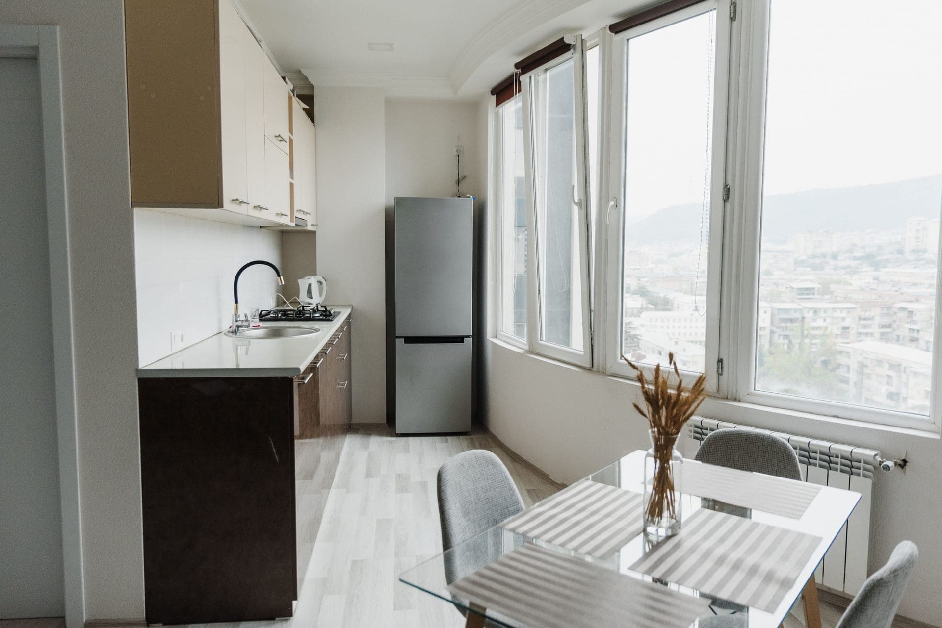 A bright minimalist kitchen with a glass table and a compact run of units