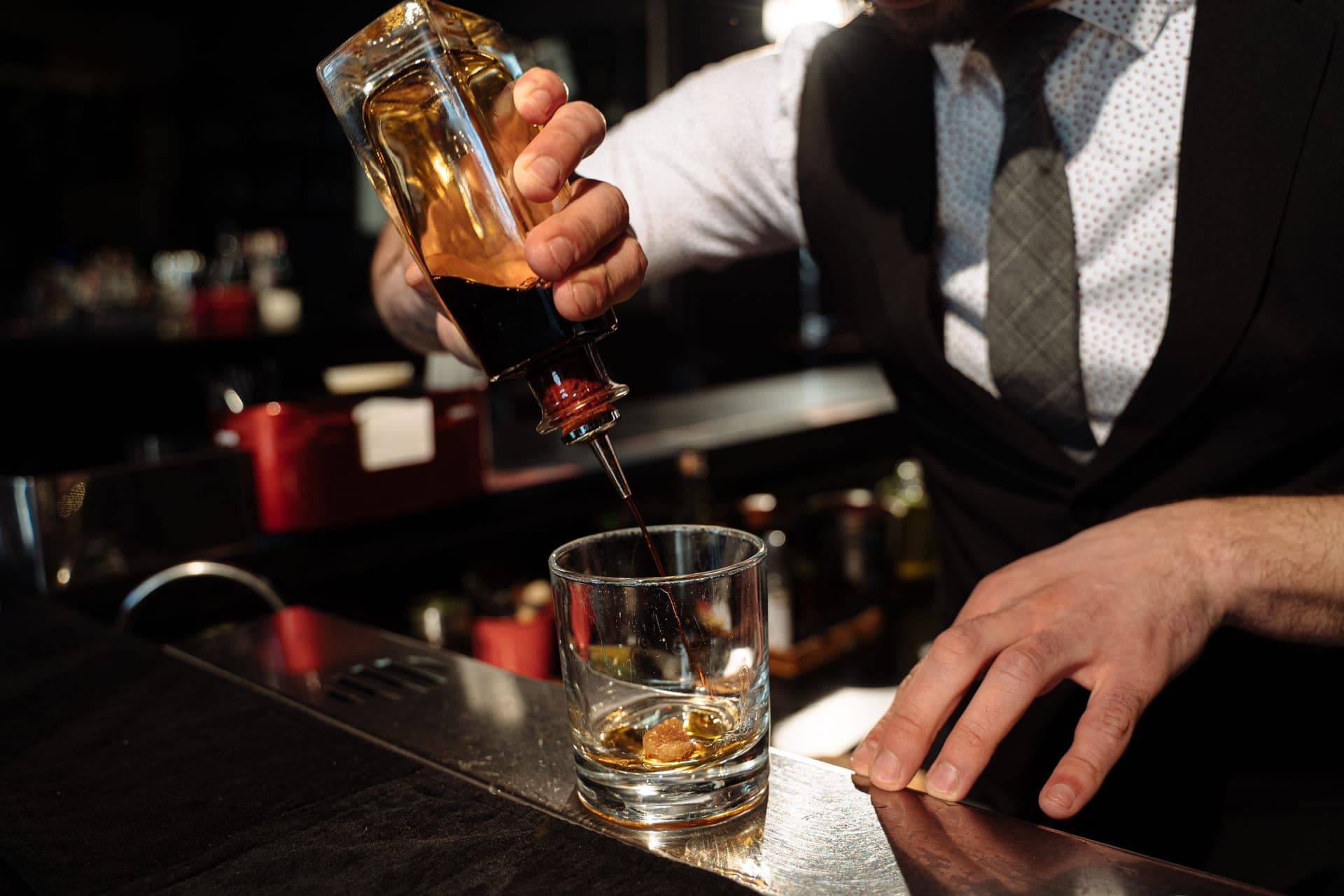 A bartender pouring whiskey into a glass at a bar counter