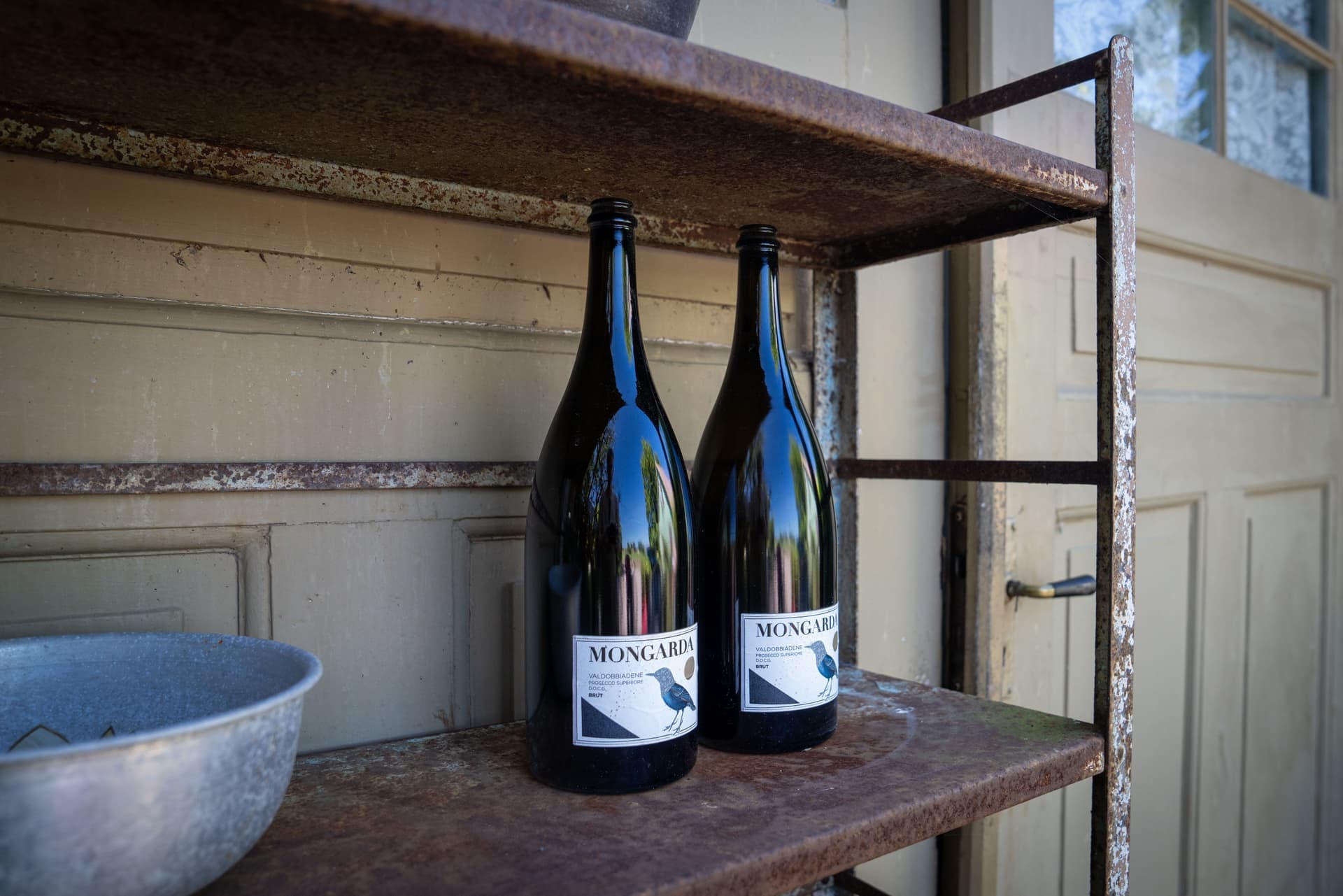 Two wine bottles standing on a plain rustic shelf