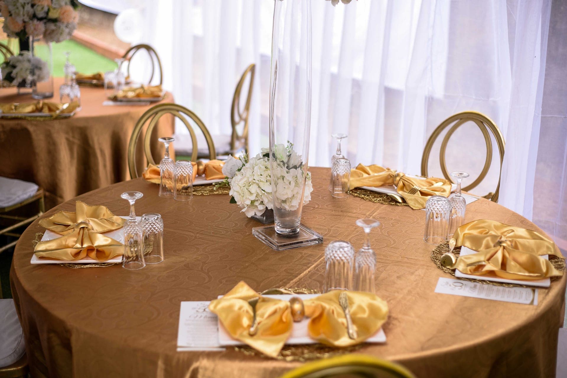 A round table set with glassware and gold-toned decor