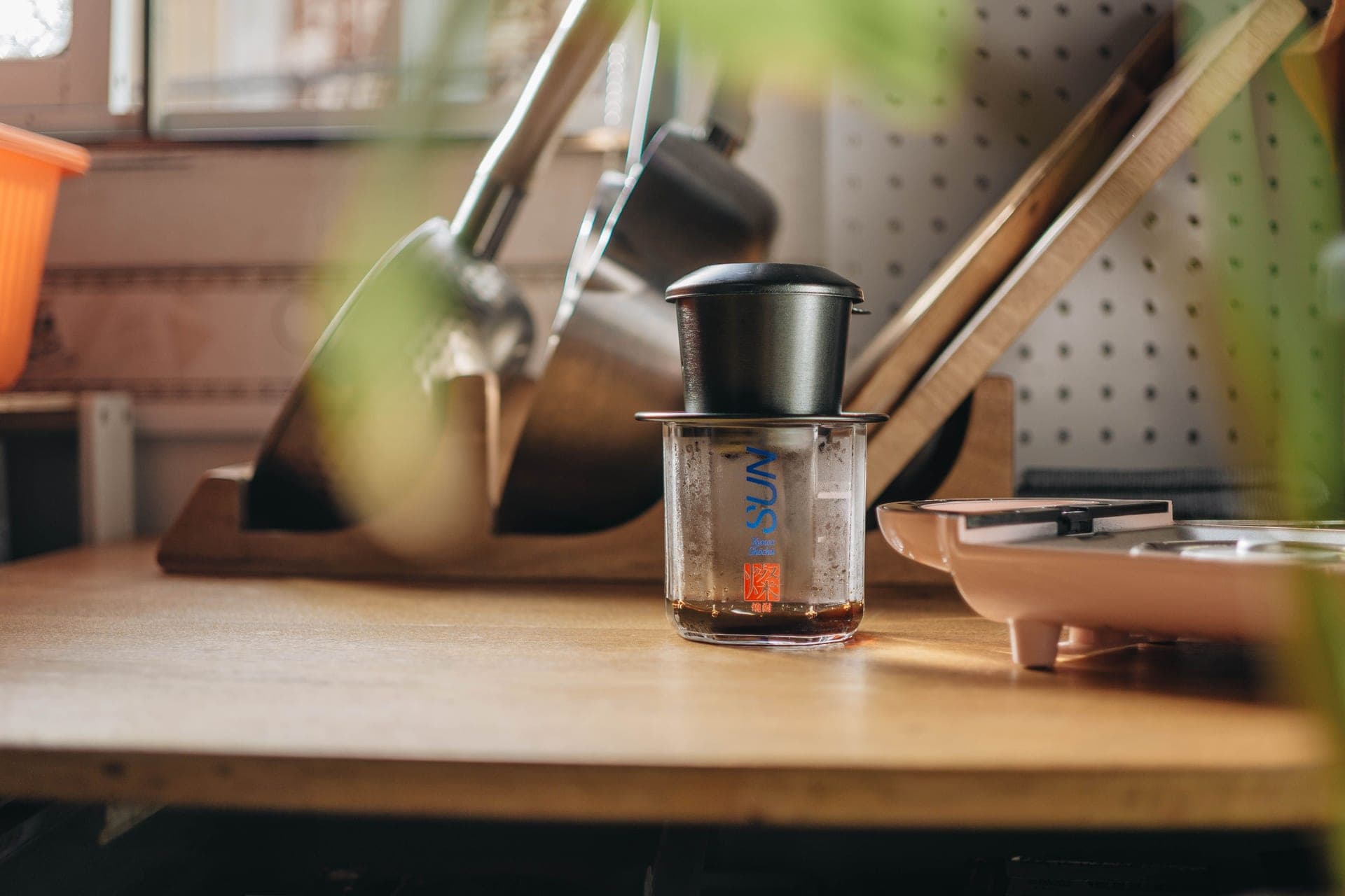 A coffee maker and kitchen tools arranged on a wooden counter