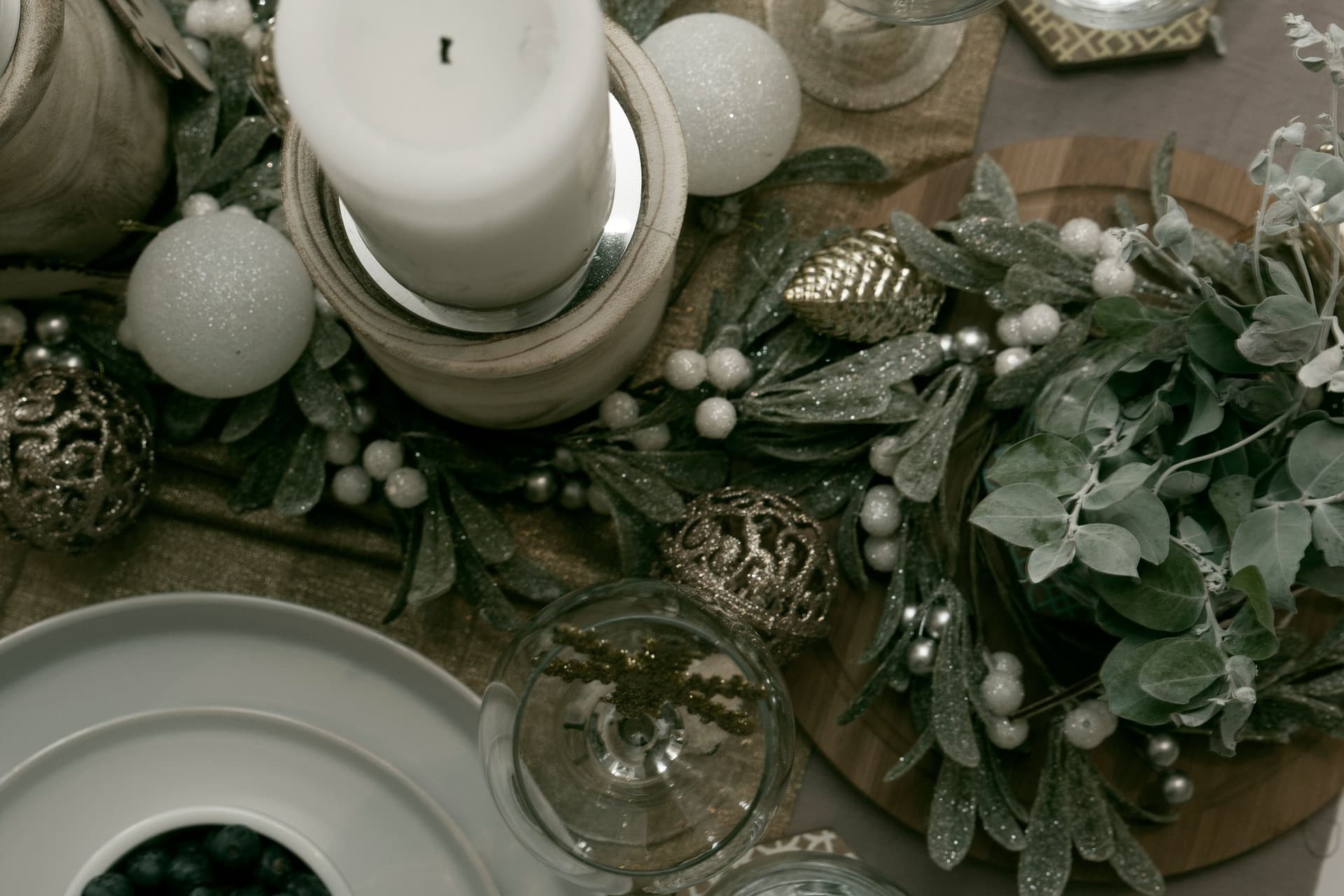 A festive table arrangement with a candle, greenery and ornaments