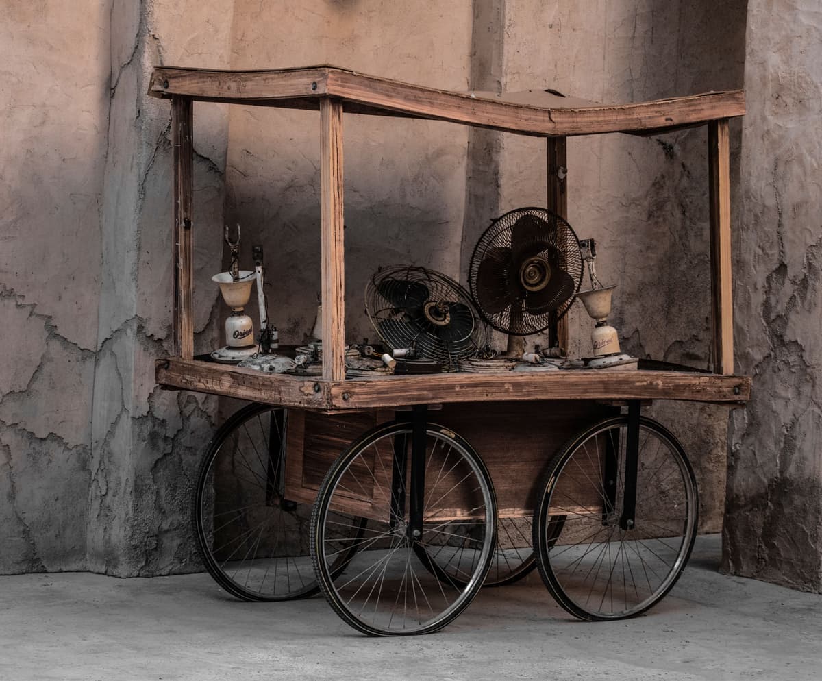 A rustic wood and black metal serving cart holding bottles