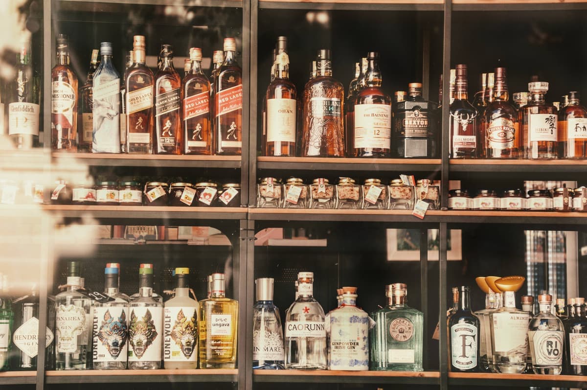 Bottles arranged in a row on the top shelf of a bar cart
