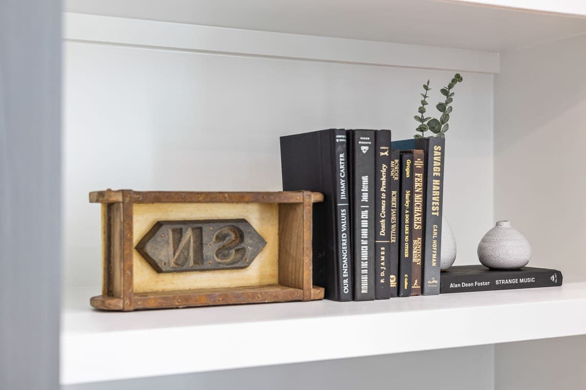 A styled shelf vignette with a tray, glassware and a small arrangement of flowers