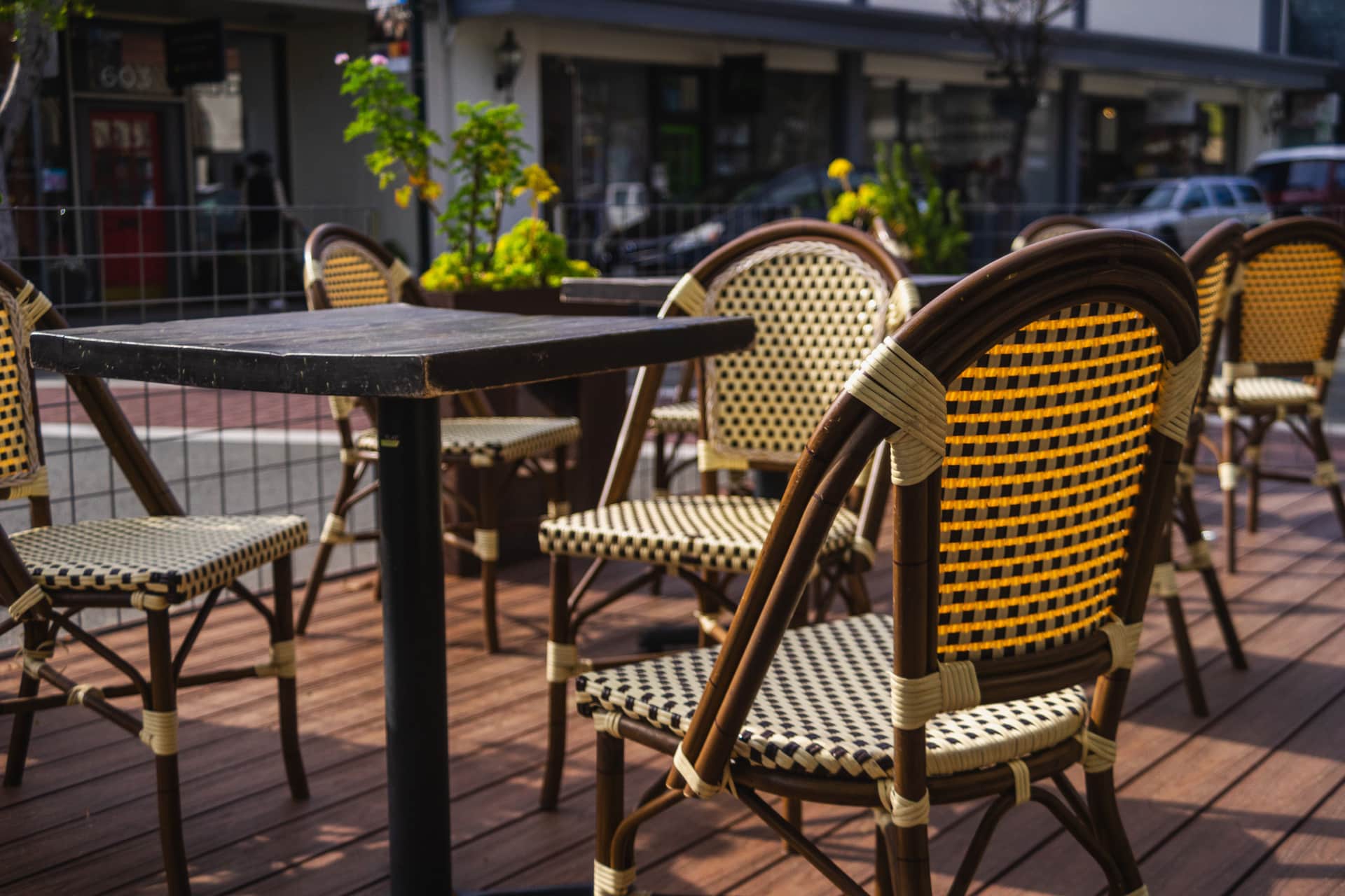 Wicker chairs and tables set out on a sunny paved terrace