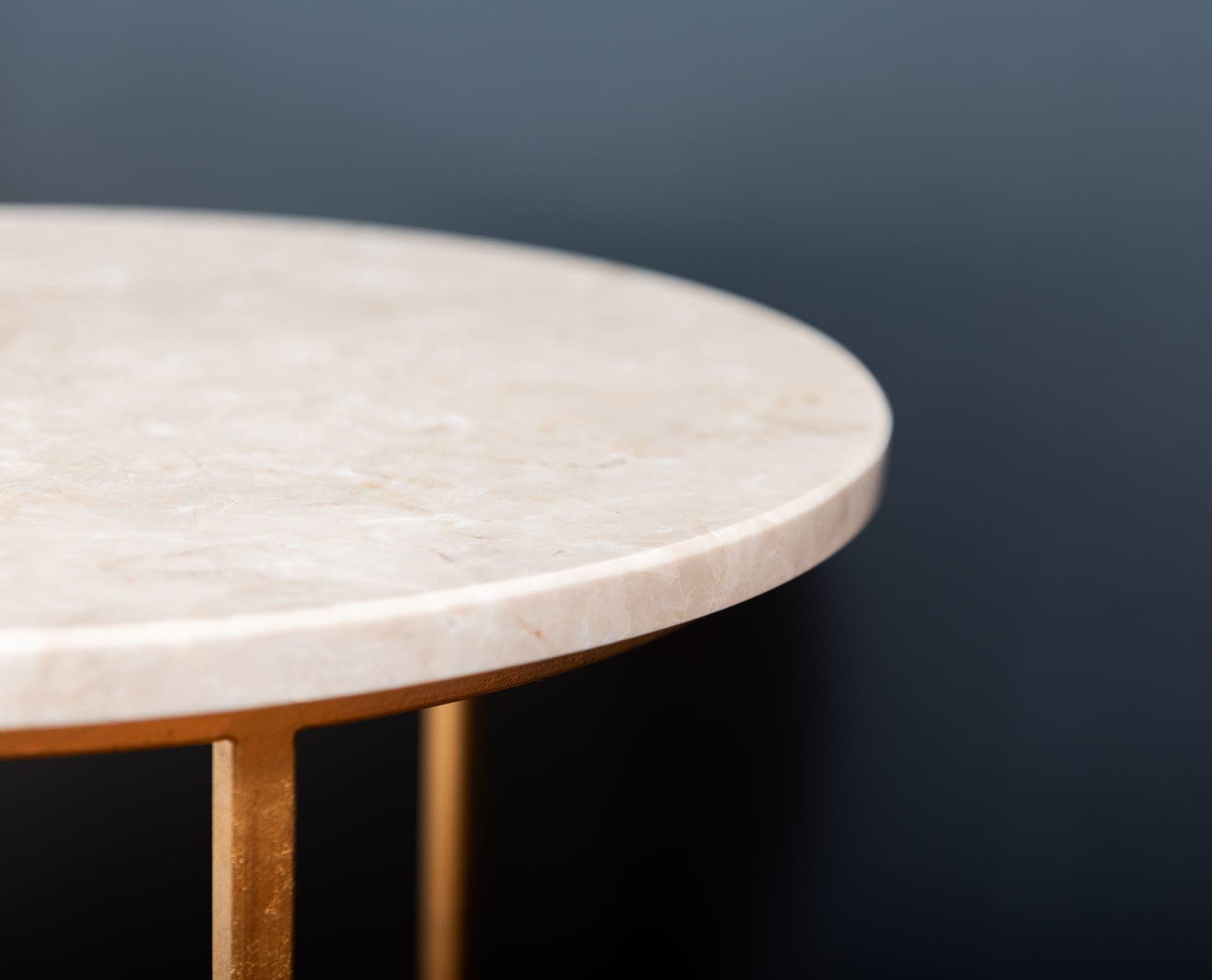 A round marble side table on a golden stand in a dim interior