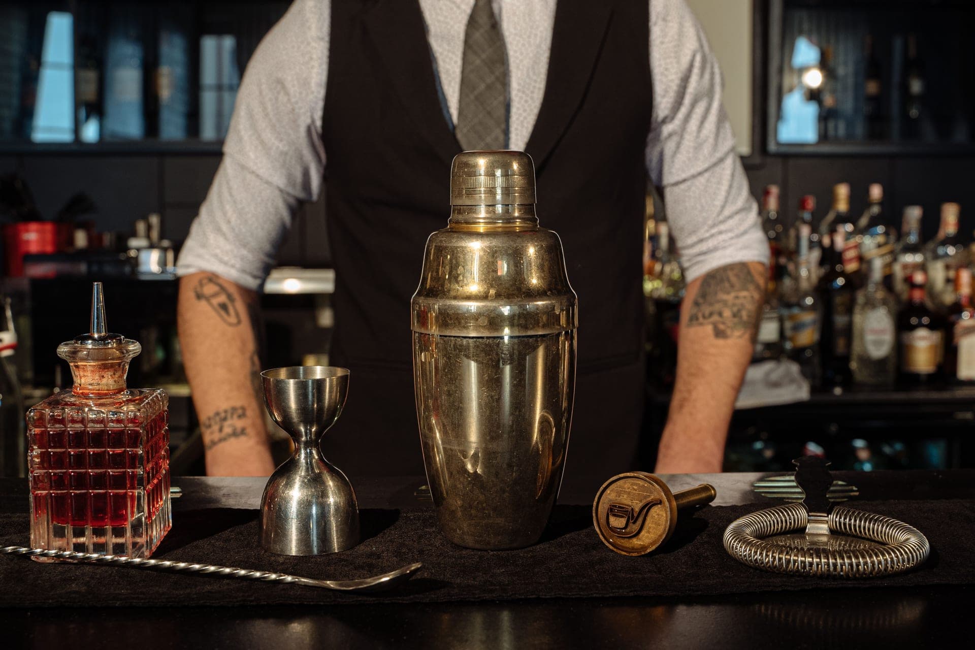 A cocktail shaker and bar tools arranged on a counter