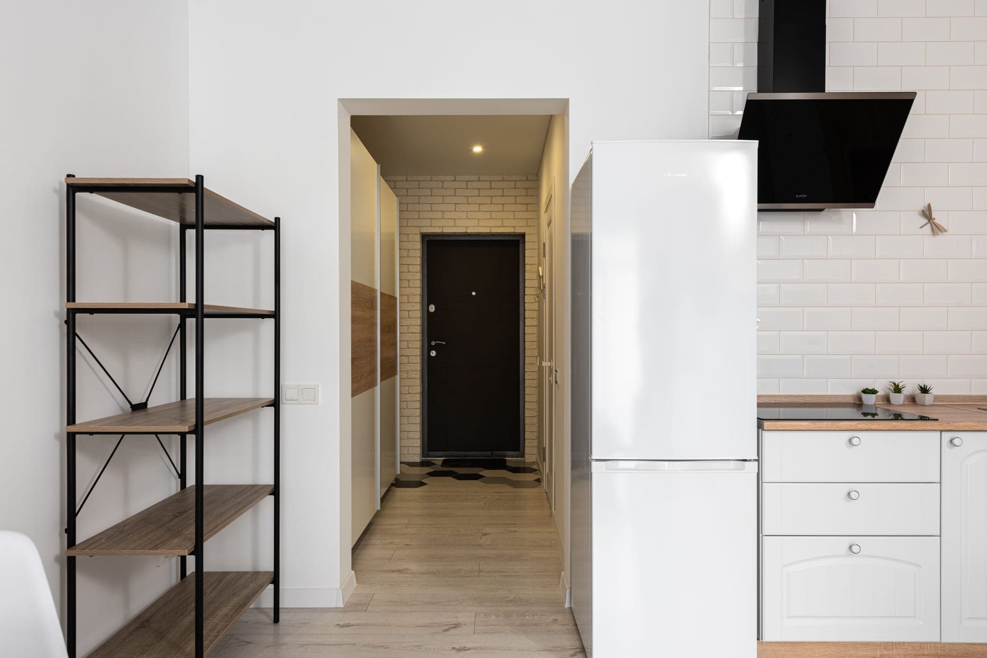 A narrow passage in a bright apartment with a slim run of shelving against the wall