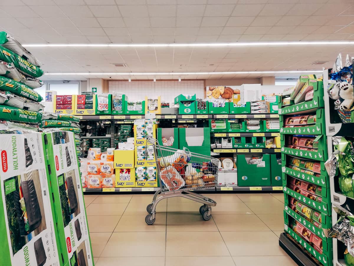 A three-shelf metal trolley photographed from the side against a plain wall