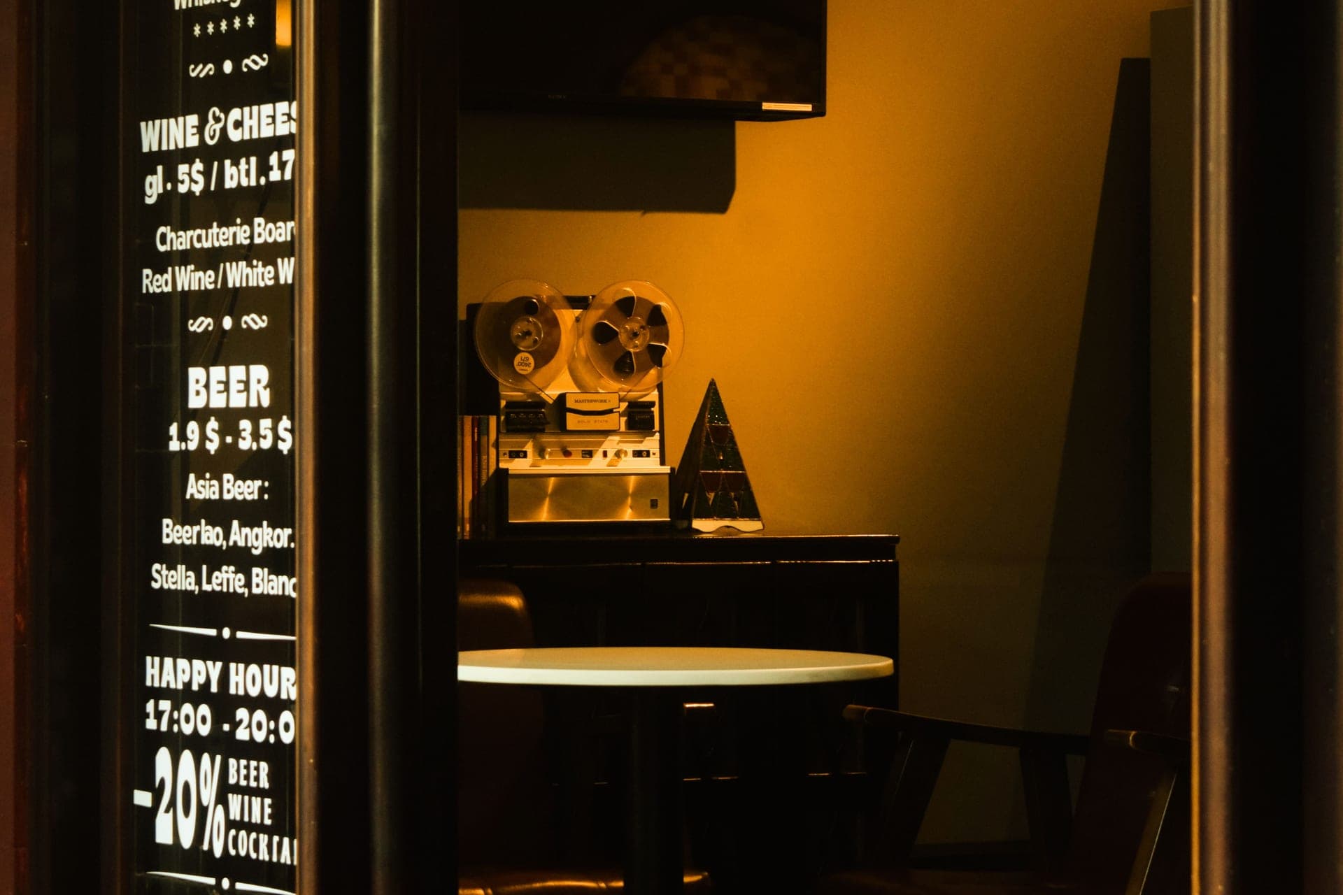A vintage bar interior with a reel-to-reel tape recorder and happy hour signage