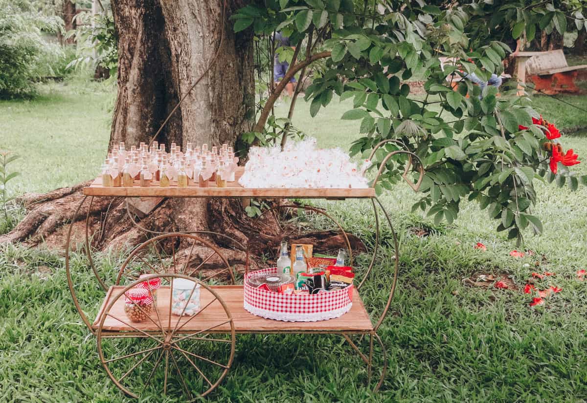 A rolling drinks cart with two shelves standing beside an armchair