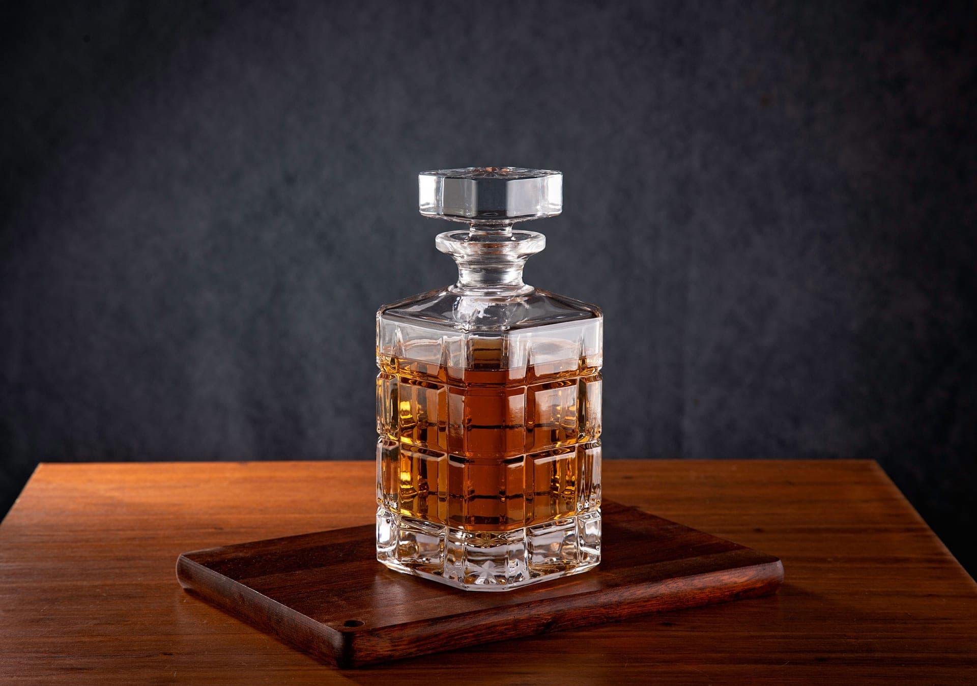 A whiskey decanter of amber spirit on a wooden table