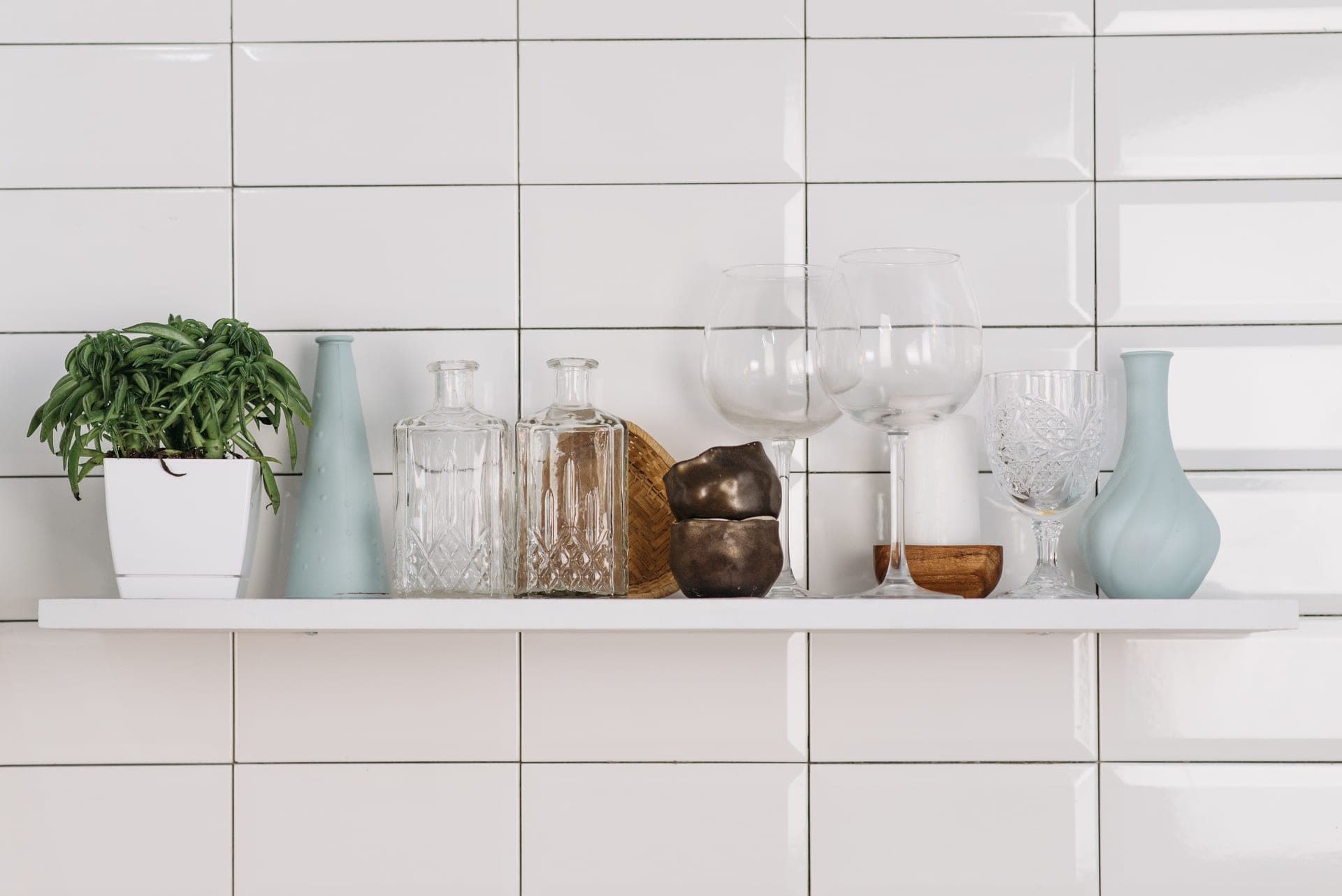Glassware, ceramics and plants arranged on a white kitchen shelf