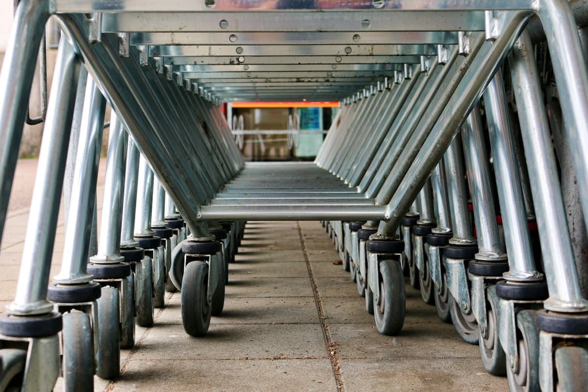 A close view of a caster wheel and lower shelf on a metal serving cart