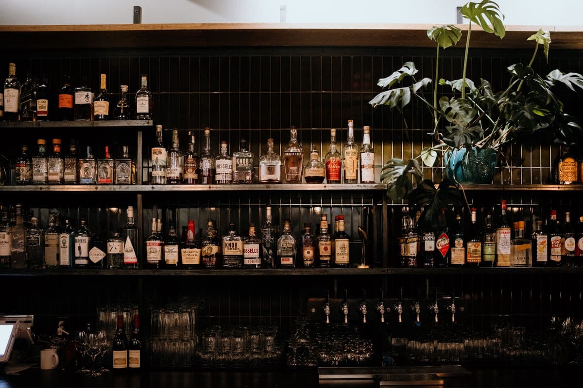 Bottles, a shaker and stemmed glasses arranged on the top shelf of a cart
